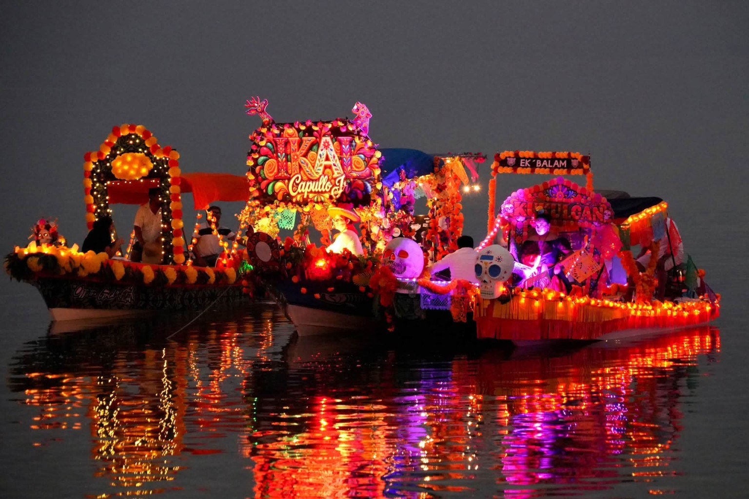 Lanchas adornadas e iluminadas reflejan sus colores sobre la bahía de Calderitas.