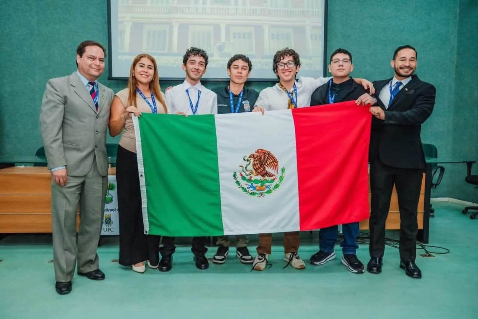 Integrantes de la delegación mexicana posan con la bandera nacional en Brasil